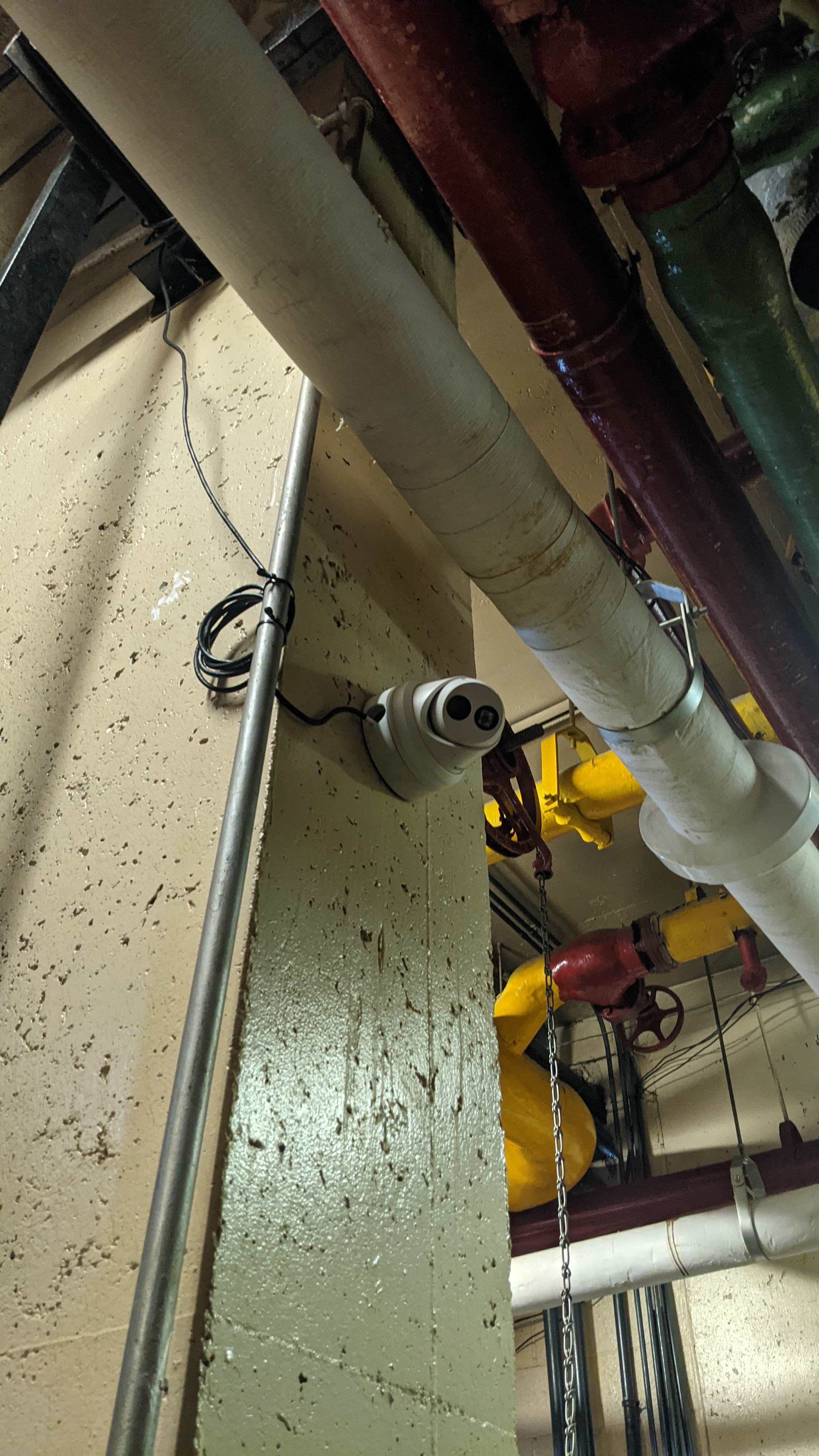 Security camera installed near mechanical piping in an industrial utility space