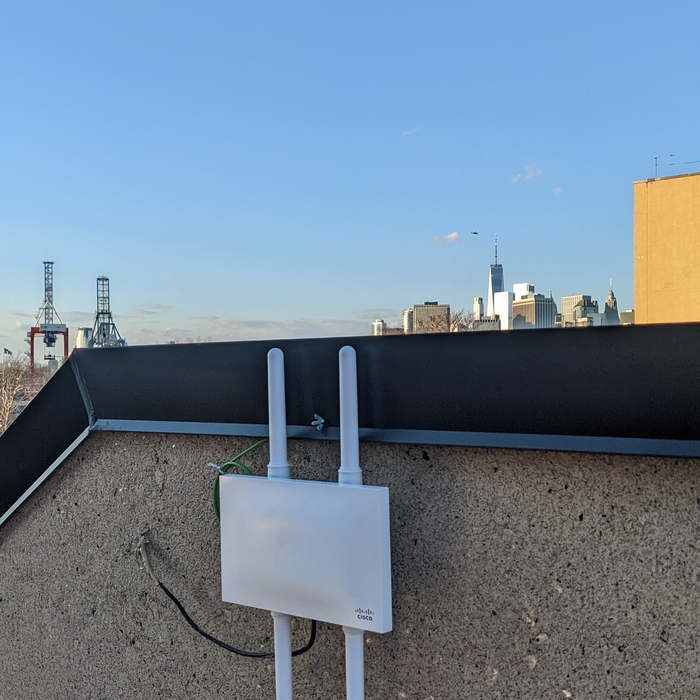 Cisco wireless access point mounted on a NYC rooftop with the Manhattan skyline in the background