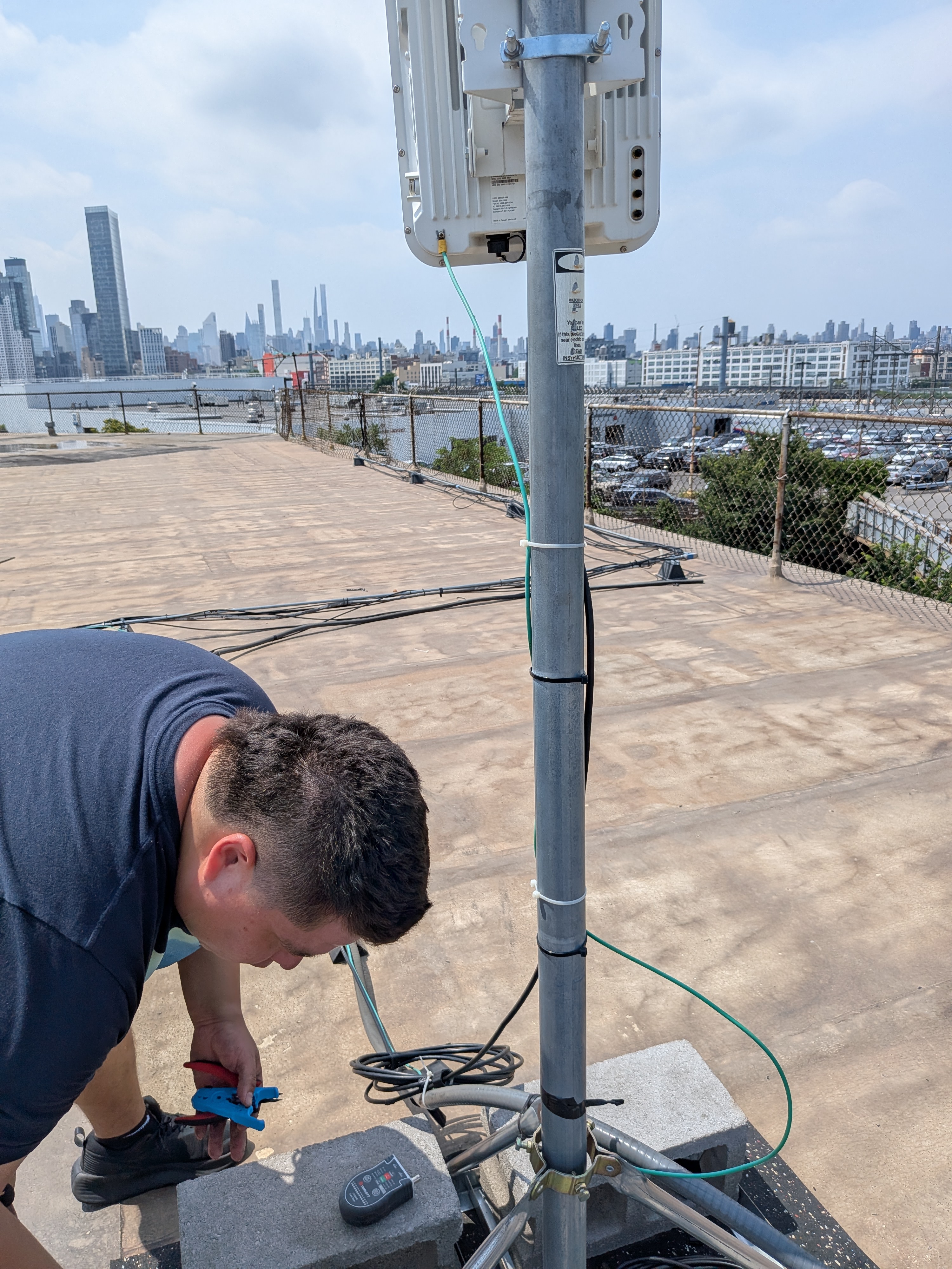 Prelinium technician terminating cable on a rooftop wireless installation overlooking the NYC skyline