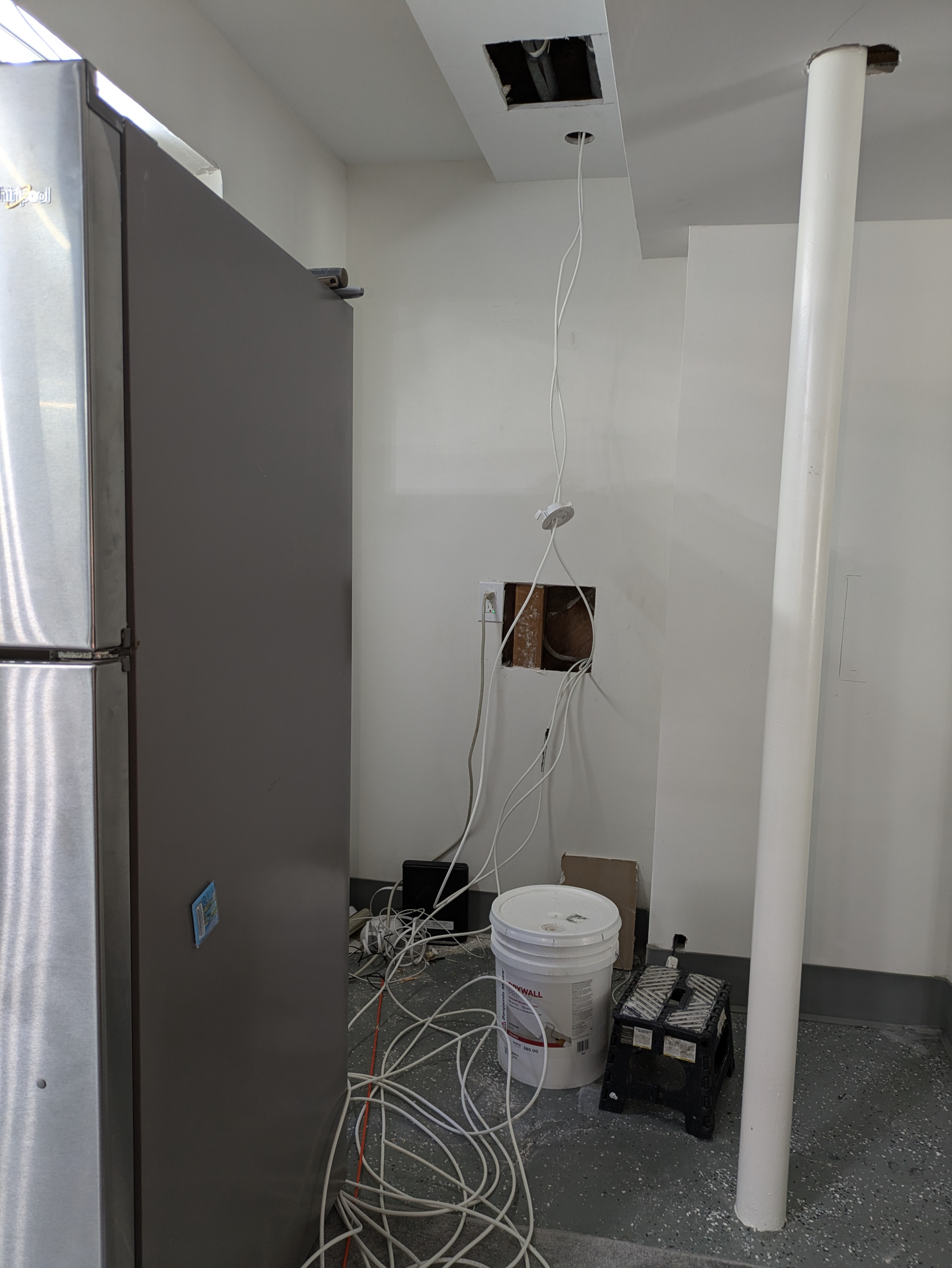 Cable run through a ceiling opening down to a floor outlet in a utility room