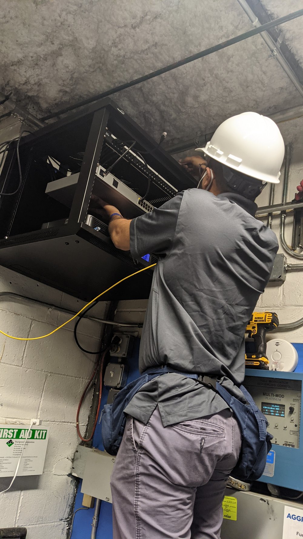 Prelinium technician mounting and wiring a network patch panel and switch in a server rack